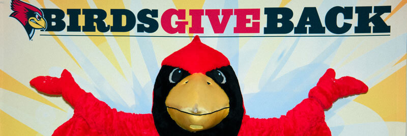 Reggie Redbird stands in front of a background that reads 'Birds Give Back'.